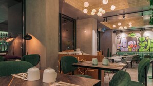 A modern restaurant interior with green upholstered chairs, wooden tables, and a graffiti wall. - Pestana Lisboa Vintage City Center Suites (Lisbon)
