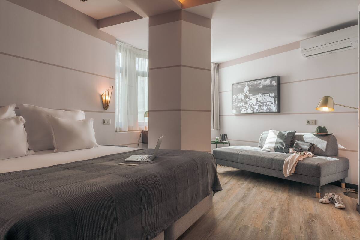 A modern bedroom with a large bed, a sofa, and a desk.