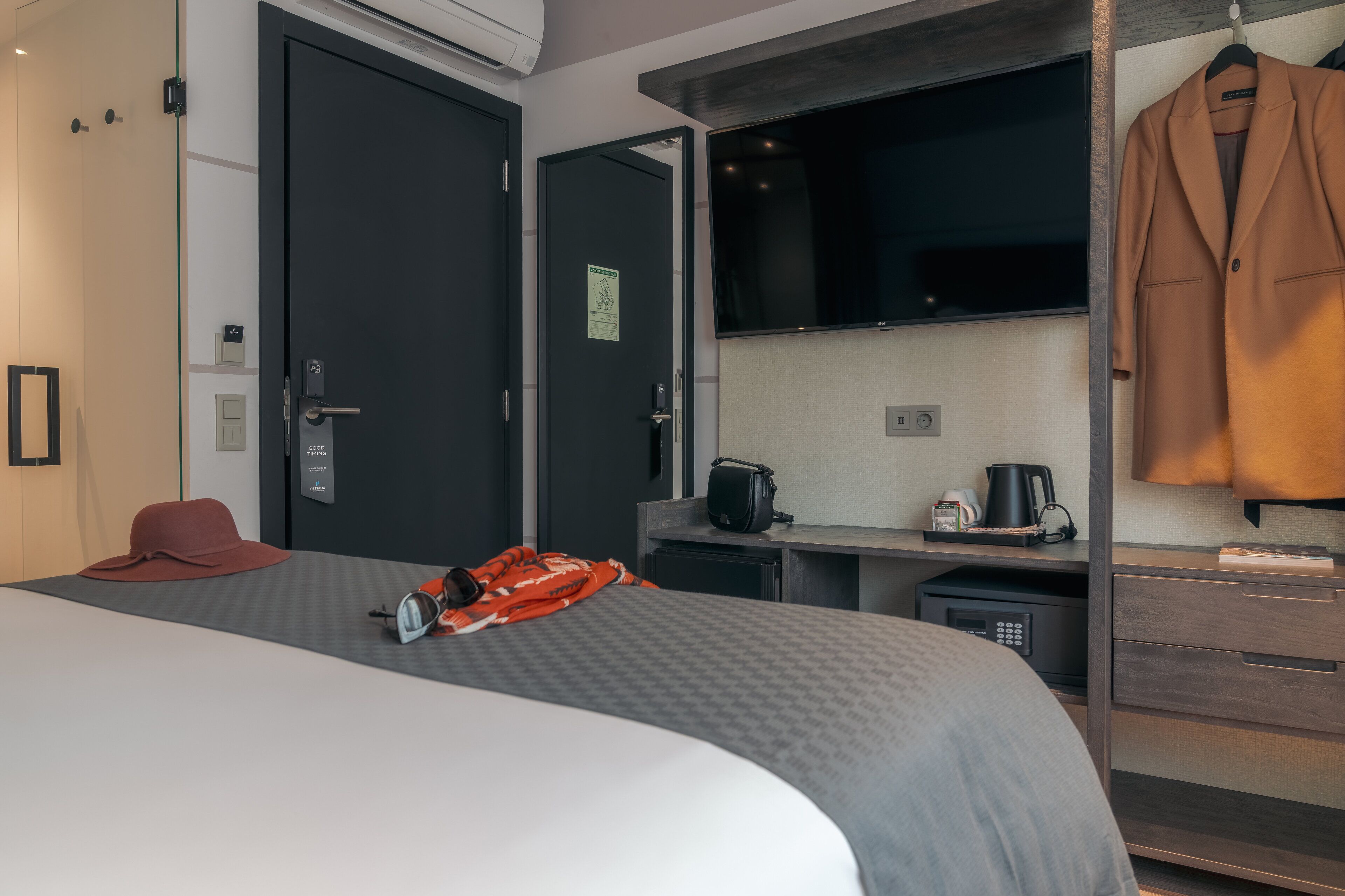 Ein Hotelzimmer mit Bett, Schreibtisch, Fernseher und Kleiderhaken.