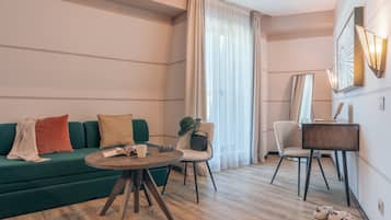 Ein stilvolles Wohnzimmer mit einem grünen Sofa, einem runden Holztisch und einem kleinen Schreibtisch mit Stuhl.