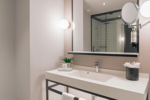 Un bagno moderno con un lavandino bianco, uno specchio e uno spazio doccia.