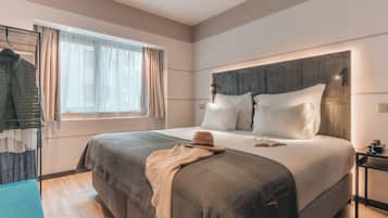 Habitación de hotel con una cama grande, una mesita de noche, una ventana con cortinas y un armario.