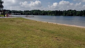 A grassy area with a lake, a dock, and a playground with red equipment. - Apartment right on the Dutch border (Oeding)