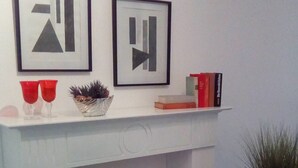 A white console table with two framed abstract artworks, a small potted plant, and a few books. - Apartment right on the Dutch border (Oeding)