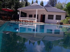 A swimming pool with a white building in the background, surrounded by greenery. - 2 Bedroom Bungalow Mtwapa (Mtwapa)