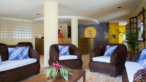 Un vestíbulo con sofás de mimbre, un mostrador de recepción y una pared decorativa.