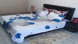 A bedroom with a bed, a nightstand, a dresser, a wardrobe, and a floral rug. - Furnished apartment in Marrakech AT10 (Marrakech)