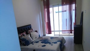 A bedroom with a bed, a TV, and a view of the outside through a sliding door. - Furnished apartment in Marrakech AT10 (Marrakech)