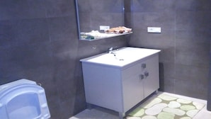 Une salle de bain avec un lavabo blanc, un miroir et des toilettes.