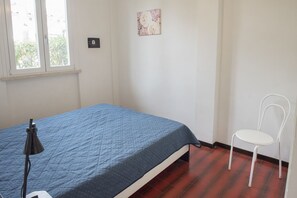 A bedroom with a bed, a chair, a lamp, a window, and a wall-mounted light switch. - M104 - Marcelli, villa with garden 200 meters from the sea (Marcelli)