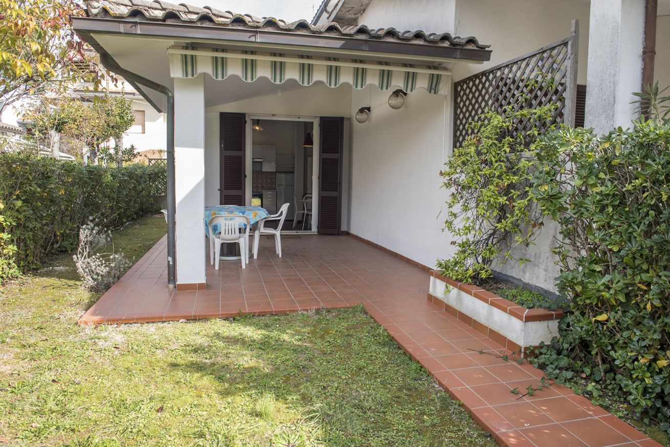 A covered patio with a table and chairs, a tiled floor, and a view into the house.