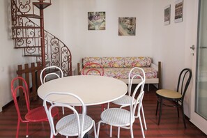 A dining area with a round table, four chairs, a spiral staircase, and a sofa with floral upholstery. - M104 - Marcelli, villa with garden 200 meters from the sea (Marcelli)