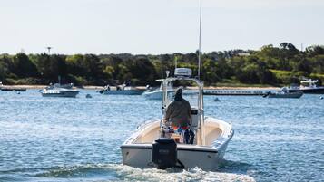 A small motorboat on a calm body of water with a dock in the background.