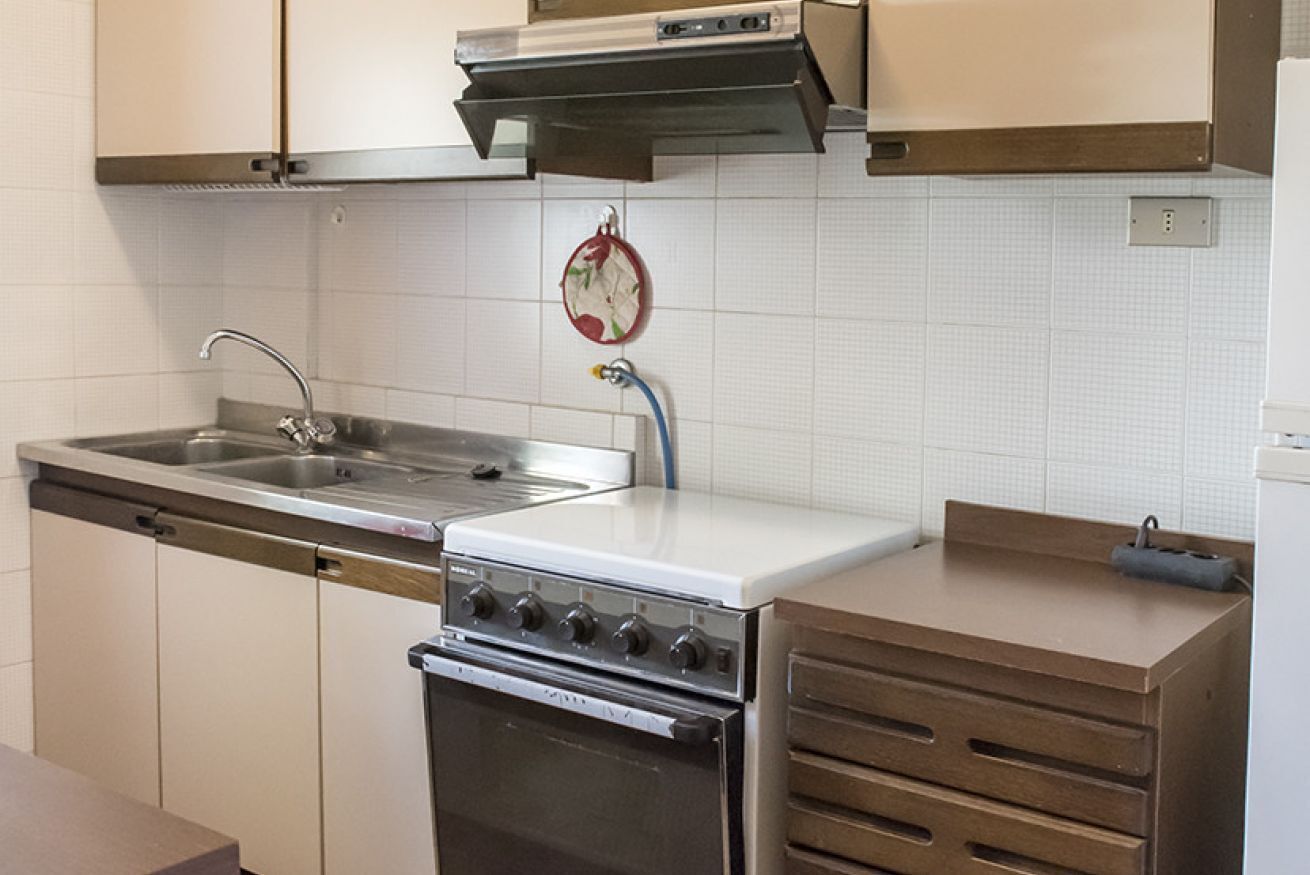 Une cuisine équipée d’un évier en acier inoxydable, d’une cuisinière et de meubles de rangement en bois.