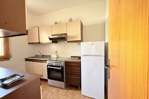 Een keuken met een fornuis, oven, spoelbak en een koelkast.