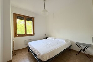 Een slaapkamer met een bed, een raam, een radiator en een tafel.