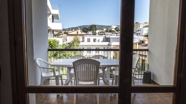Uma varanda com mesa e cadeiras, vista para a cidade e céu limpo.