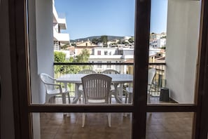 A balcony with a table and chairs, a view of the cityscape, and a clear sky.