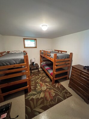 Une chambre avec deux lits superposés, une petite table avec une lampe, une commode et une fenêtre donnant sur un beau paysage.