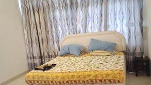 A bedroom with a bed, curtains, and a checkered rug. - 3 Bedroom Apartment In Nyali (Mombasa)