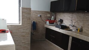 A kitchen with a tiled backsplash, a window, and a countertop with various appliances. - 3 Bedroom Apartment In Nyali (Mombasa)