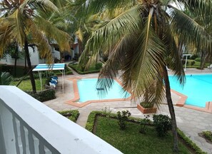 A swimming pool surrounded by palm trees and a small garden area. - 3 Bedroom Apartment In Nyali (Mombasa)