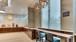 Un espace bar moderne avec un comptoir en bois, des tabourets de bar et des luminaires suspendus.