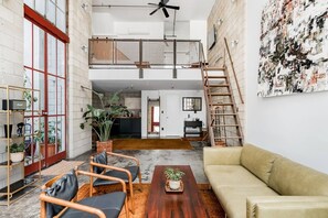 Un loft espacioso con techo alto, un nivel entre piso y una cocina moderna.