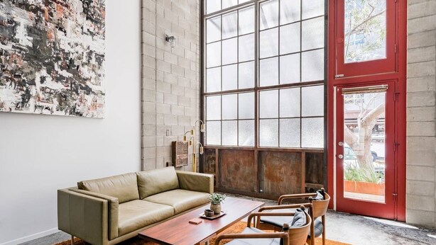 Un salon moderne avec un canapé beige, une table basse en bois et une porte rouge.