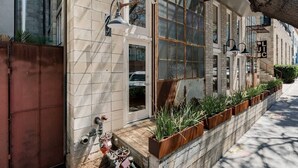 Un bâtiment doté de grandes fenêtres, d’une grille en métal et de plantes d’extérieur.