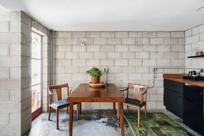 Une cuisine avec un mur en briques, une table en bois, des chaises et une plante en pot.