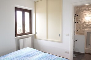 Une chambre à coucher comprenant un lit, une fenêtre, un radiateur, une armoire et un espace douche.