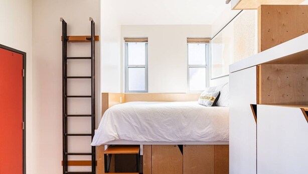 Une petite pièce avec un lit superposé, une échelle et une petite table en bois.