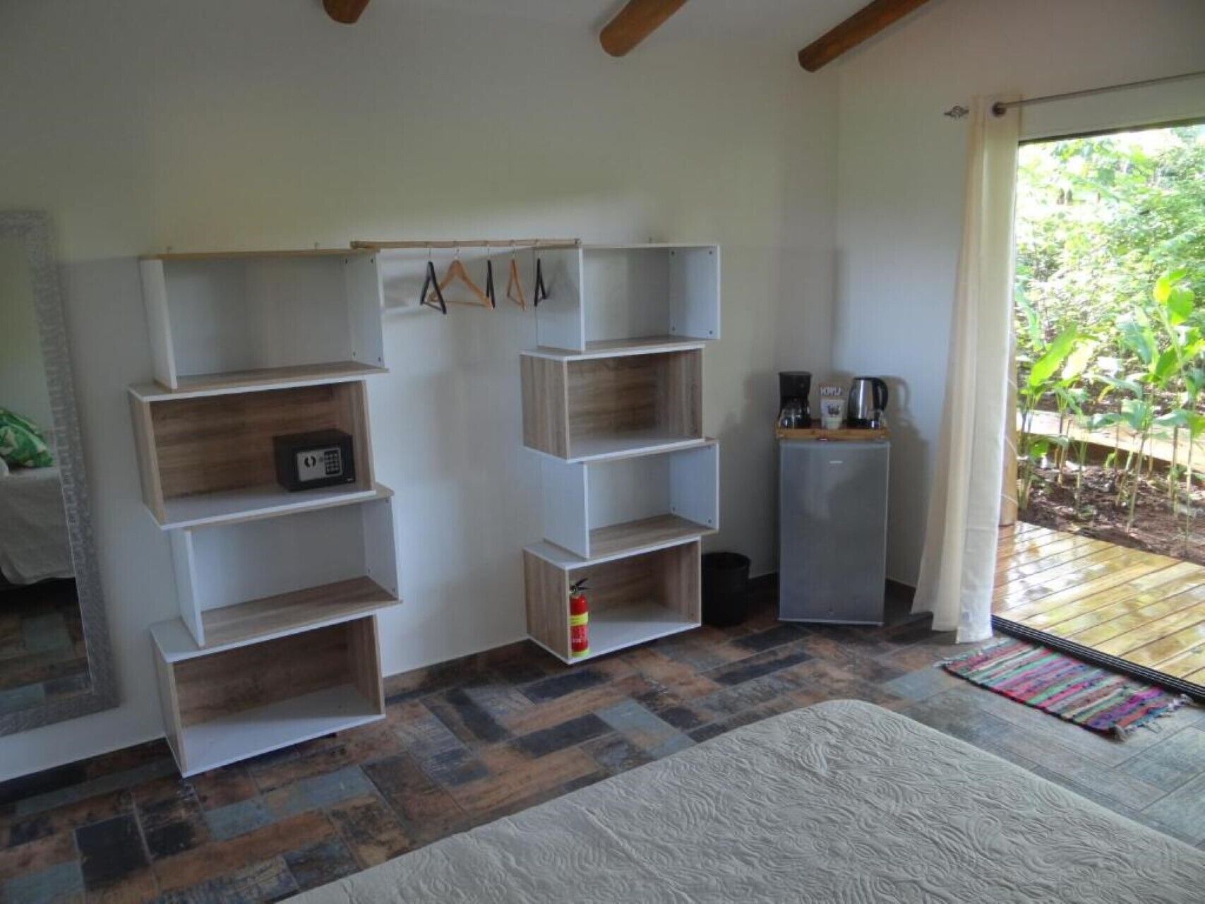 A room with a built-in shelving unit, a small refrigerator, and a coffee maker on a counter.