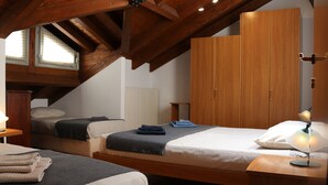 A bedroom with two beds, wooden wardrobe, and a sloped ceiling. - Lake Sunset View - Como Lake (Bellano)