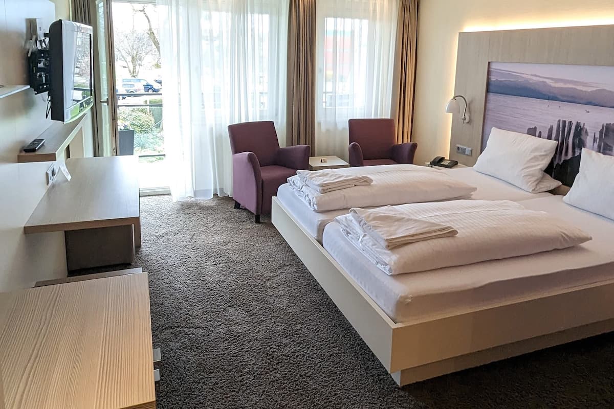 Une chambre d’hôtel avec un grand lit, un bureau, une chaise et un téléviseur.