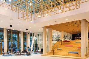 A spacious lobby with a modern staircase, large windows, and a geometric ceiling design. - Holiday Inn Express Amsterdam - North Riverside by IHG (Amsterdam)