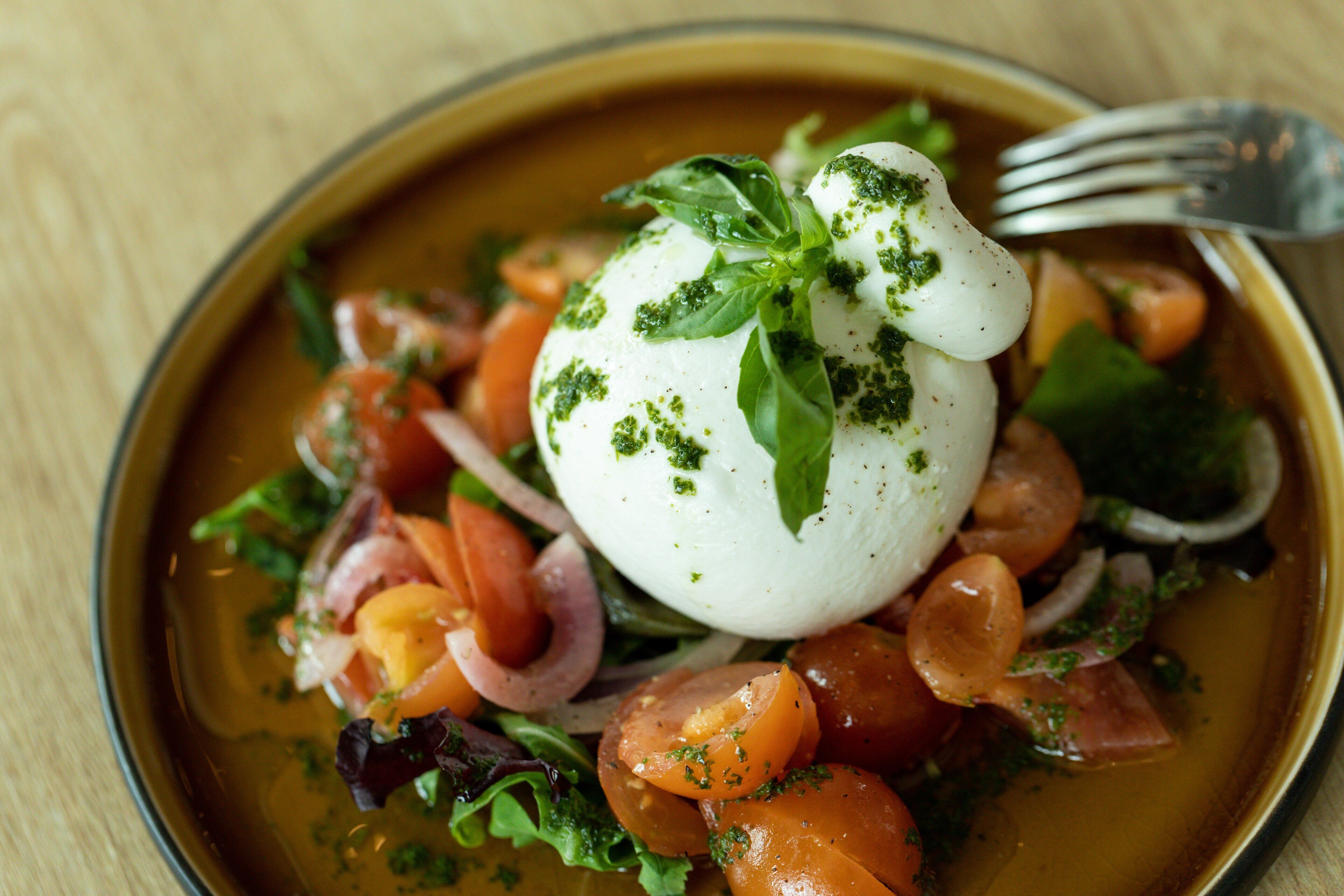 A bowl of food with a poached egg, vegetables, and herbs.