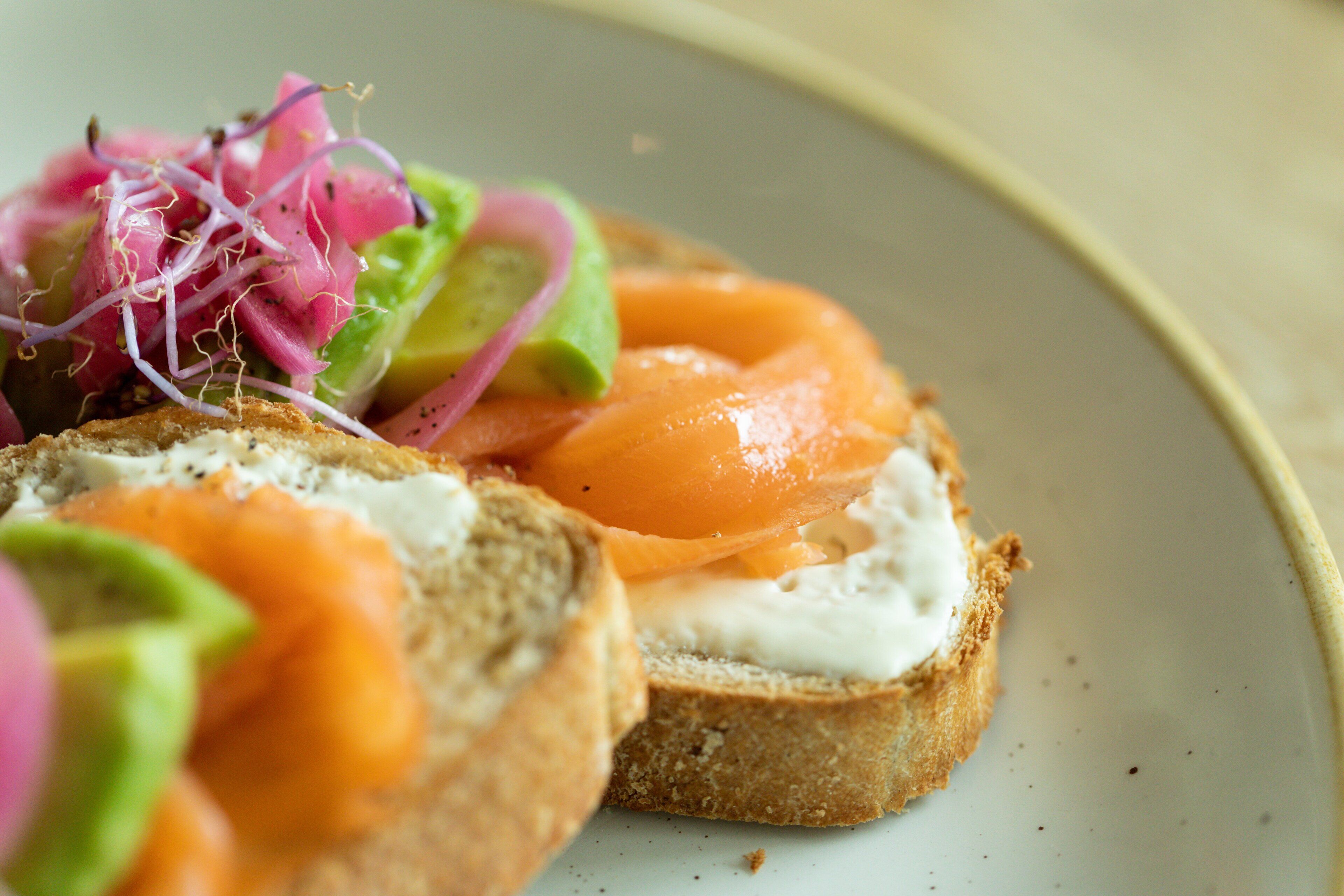 A sandwich with avocado and smoked salmon on a slice of bread.