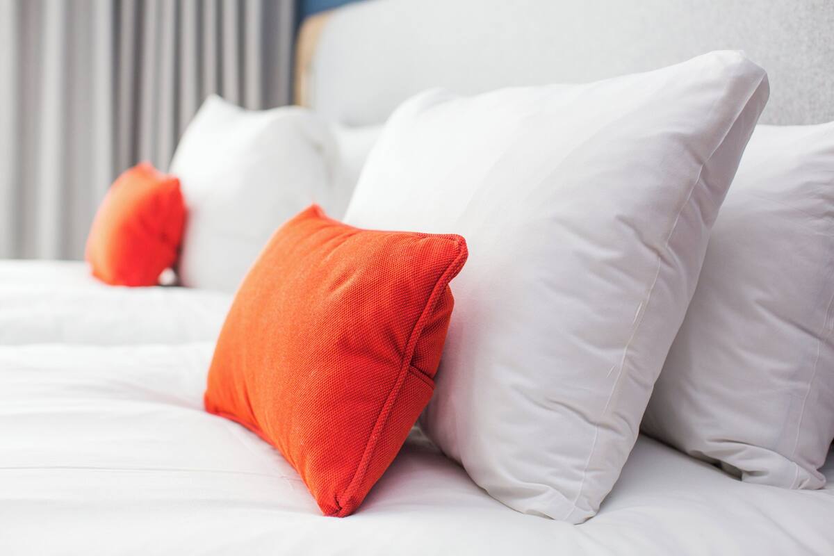 A bed with white and orange pillows.