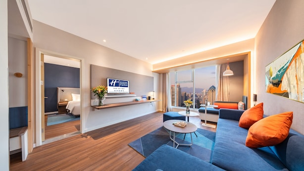 A modern hotel room with a large window, a sofa, a dining table, and a bed. - Holiday Inn Express Hangzhou Westlake East by IHG (Hangzhou)