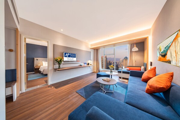 Una habitación de hotel moderna con un ventanal grande, un sofá, una mesa de comedor y una cama.