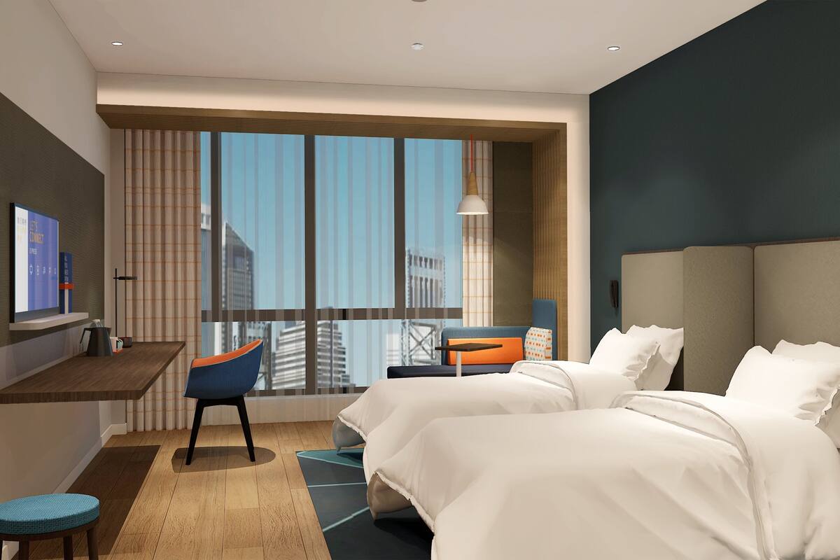 A modern hotel room with a large window, a desk, two beds, and a television.