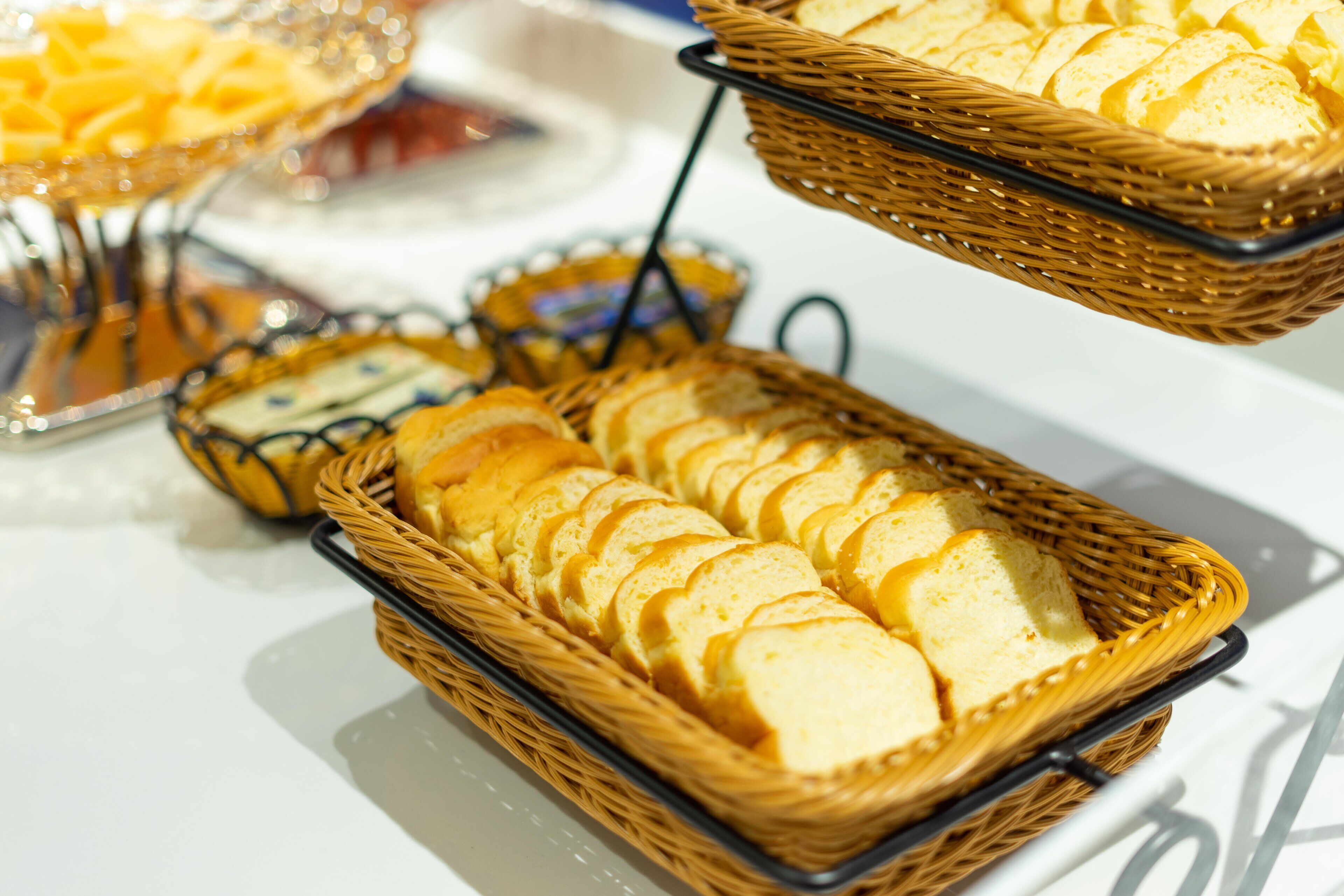 A buffet table with various food items, including bread and pastries, arranged in baskets.