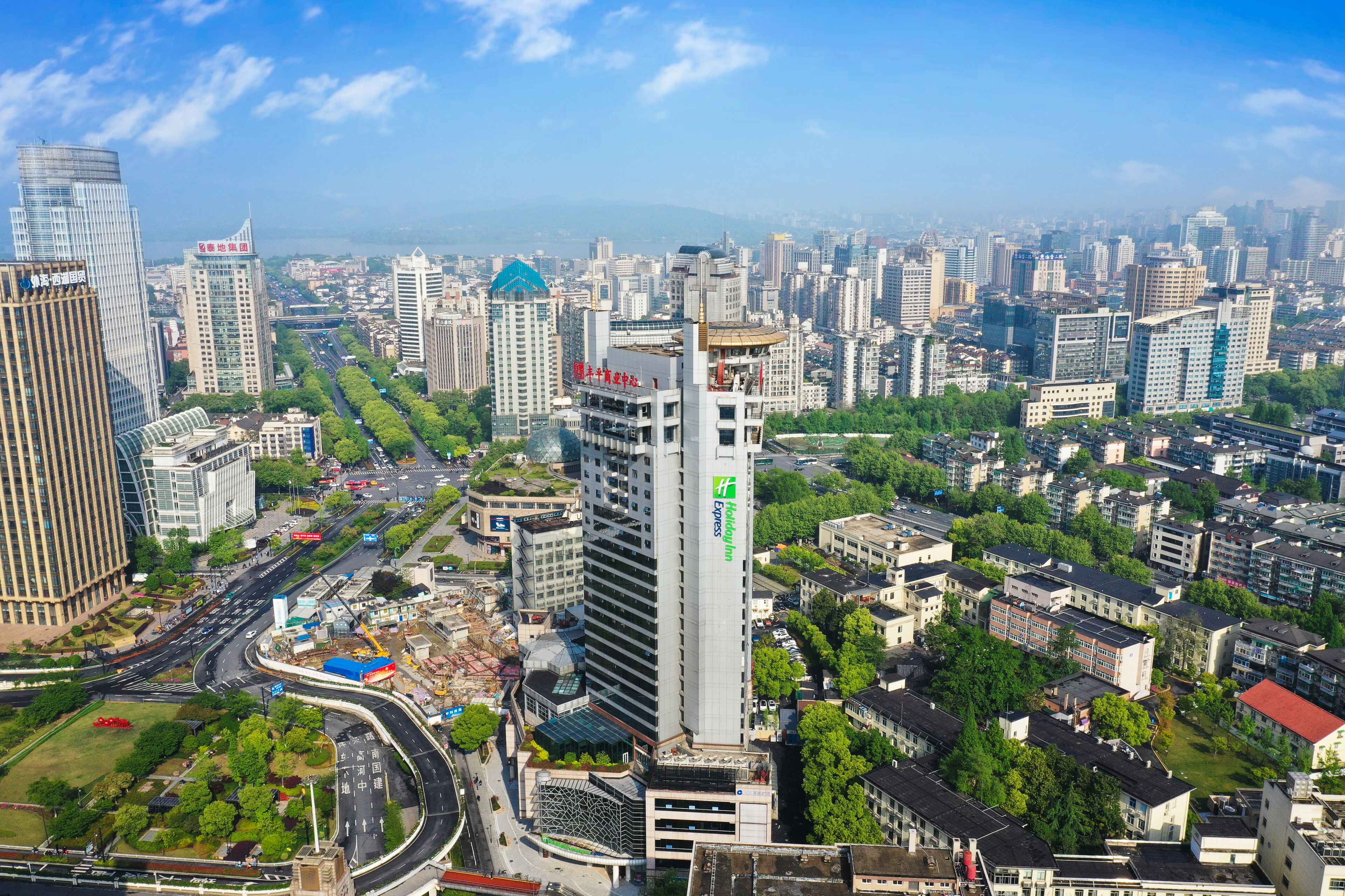 A high-rise hotel with a prominent 'Hyatt' sign, surrounded by dense urban buildings and a busy road.