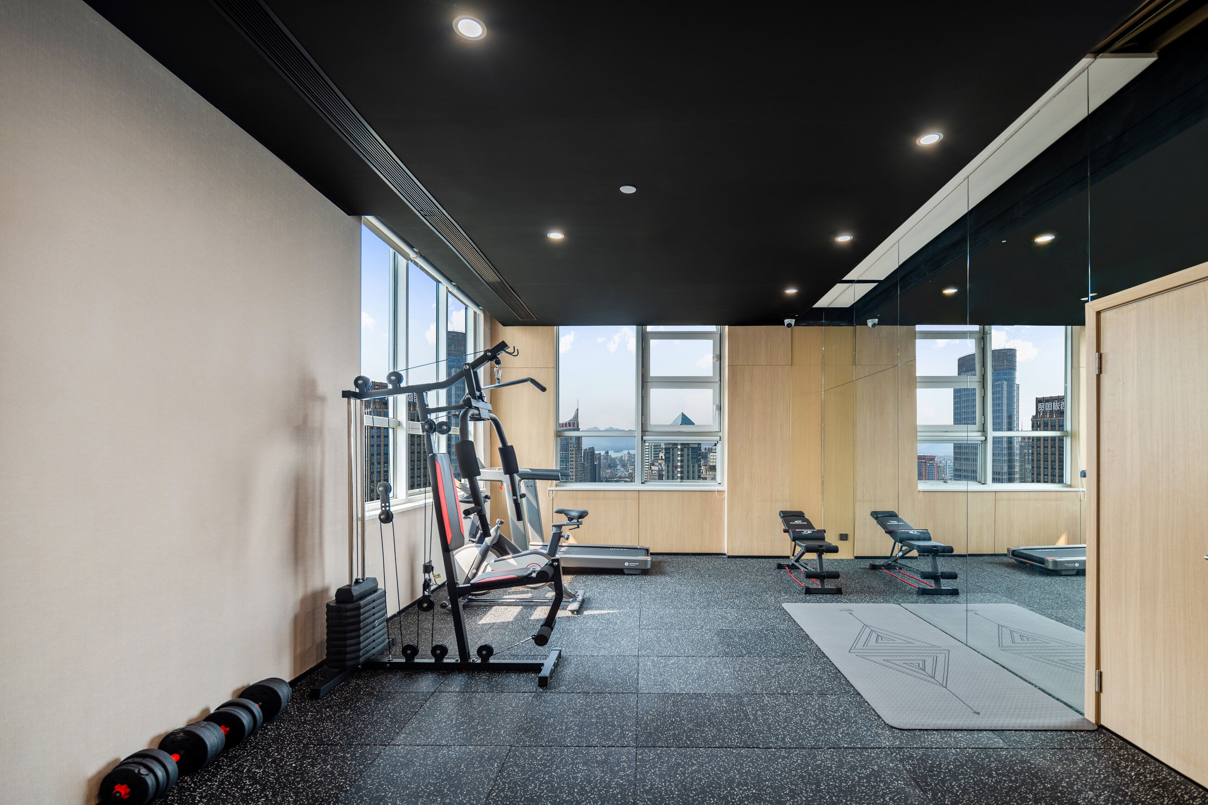 Un gimnasio con máquinas de cardio, mancuernas y una colchoneta de yoga.