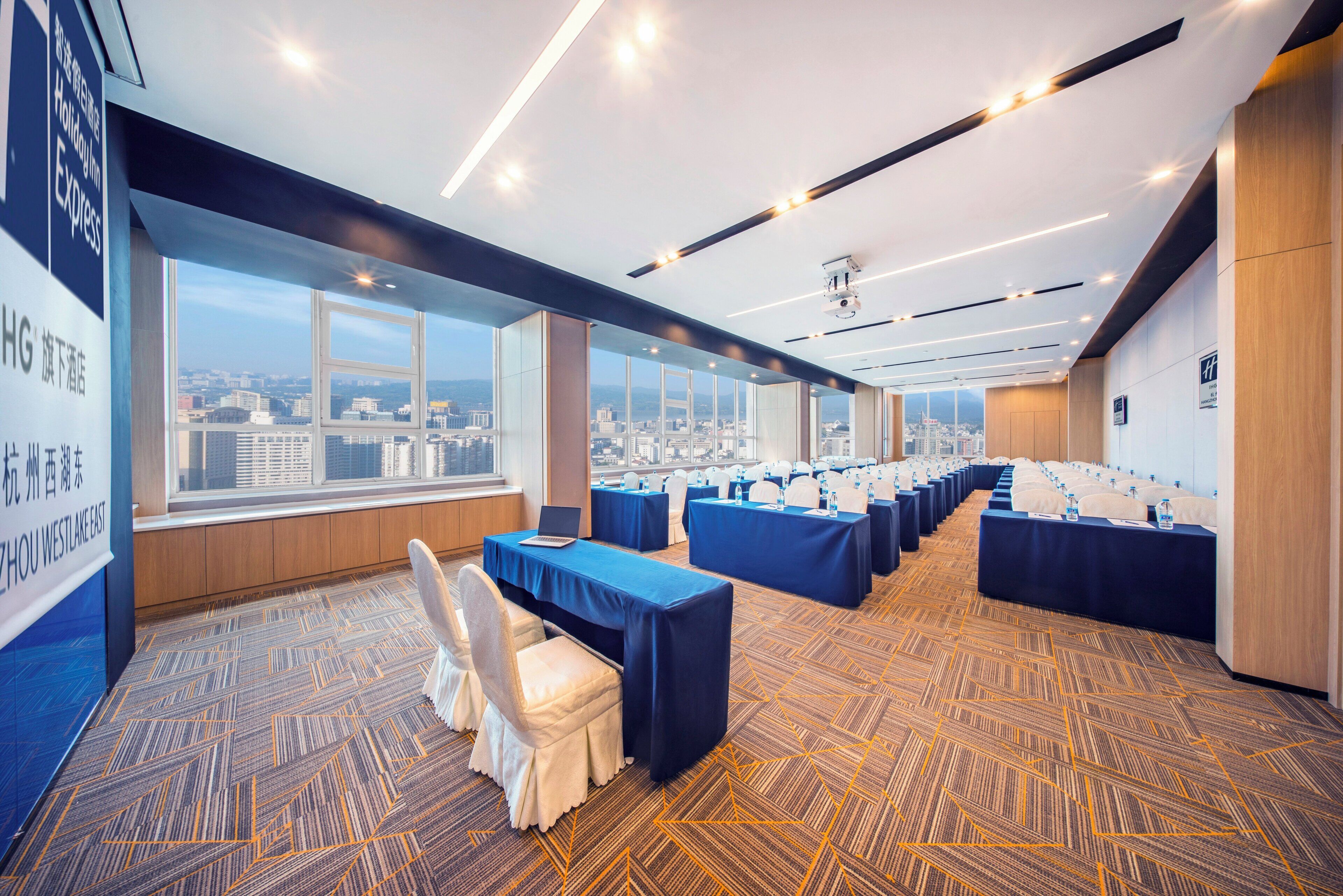 A conference room with multiple tables, chairs, and a city view.