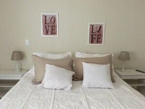 A neatly made bed with two pillows, two bedside tables with lamps, and two framed signs on the wall. - Montevideo, Centro Edificio El Pais (Montevideo)