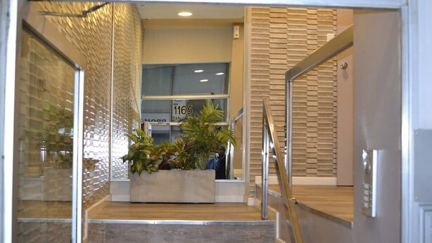 Un interior modern amb una escala, una zona de recepció i una exhibició de plantes.