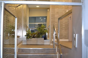 Un intérieur moderne avec un escalier, un espace d’accueil et une présentation de plantes.